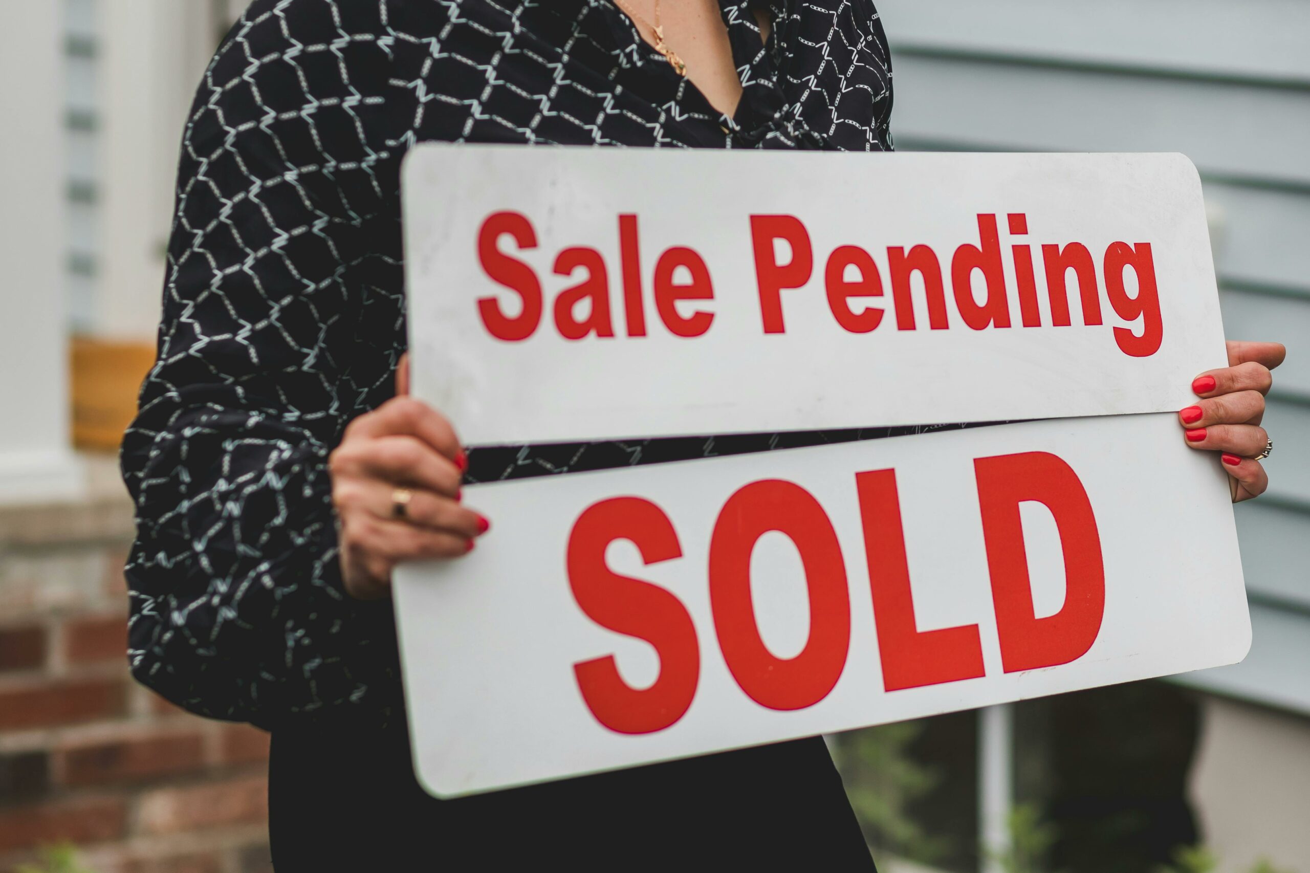 Woman Realtor holding two signs, "Sale Pending" and "Sold"