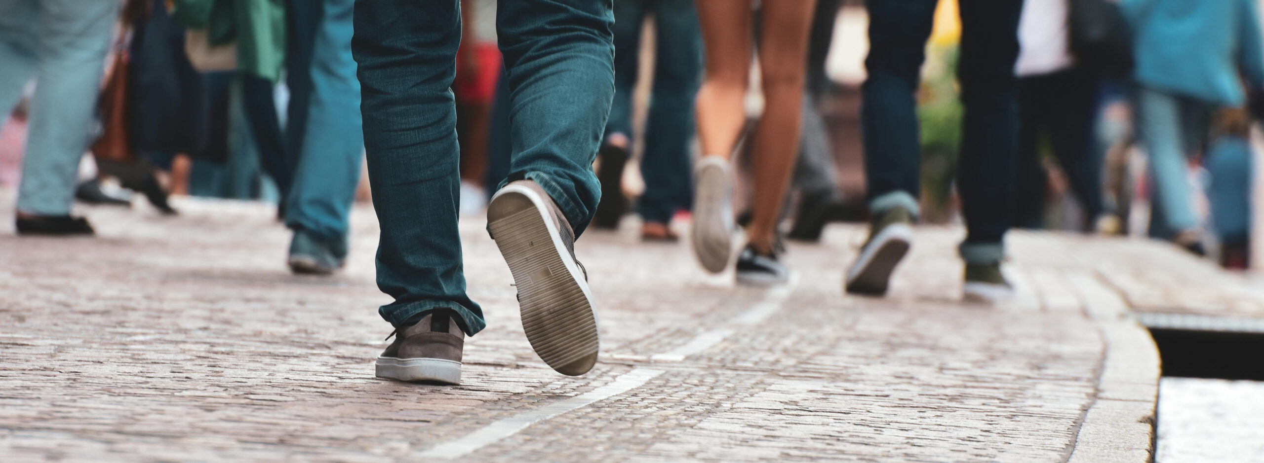 Image of people walking on a sidewalk with a focus on their feet.